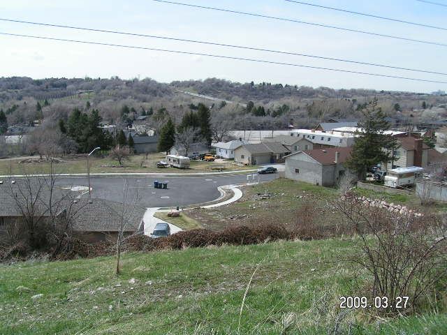 A vacant lot with a paved area surrounded by grass.